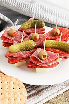 several appetizers are arranged on a plate with pickles and crackers next to them