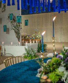 a blue table cloth with candles and flowers on it