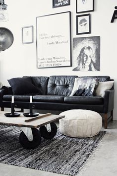 a living room with black leather couches and pictures on the wall above it's coffee table