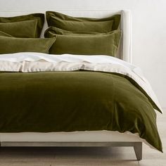 a bed with grey and white linens in a minimalistic bedroom setting on a wooden floor