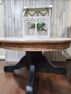 a wooden table with black legs and a white house in the back drop down window