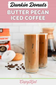 two glasses filled with iced coffee sitting on top of a counter next to doughnuts