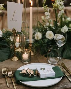 a place setting with candles, flowers and napkins