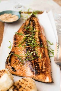 grilled salmon and potatoes on a white plate with fork and knife next to it