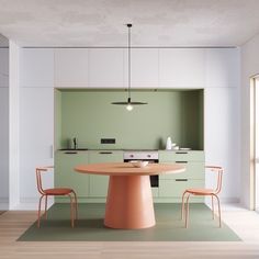 a table and chairs in a room with light green walls, wood flooring and white cabinets