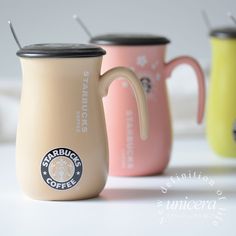 three starbucks coffee mugs are lined up in different colors and designs, one is pink, the other is yellow