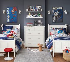 two children's beds in a bedroom with batman posters on the wall above them