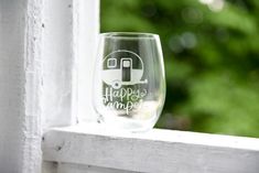 a wine glass with the words happy camper on it sitting on a window sill