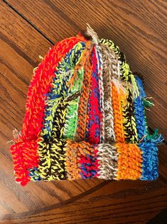 a multicolored knitted hat sitting on top of a wooden table