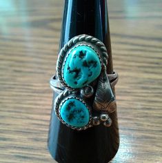 Lovely Pretty Two Stone Turquoise Unique Ring. Turquoise Nugget Stones Are Set In A Raised Bezel With Sterling Braiding Around Each Stone ,Which Highlight The Ring. A Center Sterling Pearl, A Leaf, Three Pearls At The Bottom Of The Leaf Complete The Detailed Design.Handcrafted By A Native American Navajo Artist. Size 8 1/2 Measures 7/8" X 1/2" Weight 6.2 Grams Sterling Silver New ,Never Worn, From Vintage 1980’s Collection. Western Style Turquoise Gemstone Rings, Southwestern Turquoise Teardrop Ring, Southwestern Blue Turquoise Teardrop Ring, Vintage Blue Turquoise Ring With Natural Stones, Southwestern Blue Teardrop Ring, Southwestern Teardrop Blue Rings, Adjustable Vintage Turquoise Ring With Natural Stones, Adjustable Untreated Turquoise Ring, Southwestern Multi-stone Turquoise Ring