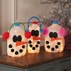 three plastic bottles decorated like snowmen with lights on them