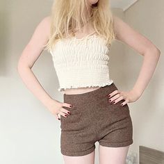 a woman standing in front of a mirror wearing short shorts and a cropped top