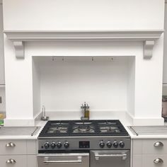 a stove top oven sitting inside of a kitchen next to a wall mounted oven hood