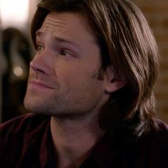 a close up of a person with long hair and a brick wall in the background