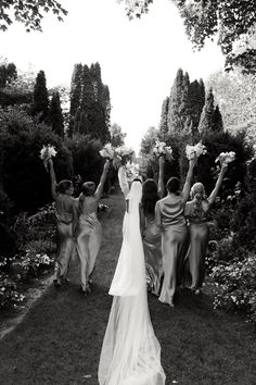 a bride and her bridal party walking down the path in black and white photo