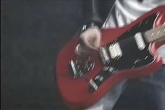 a man is playing an electric guitar with his hand on the top of its body