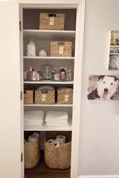 an open closet with baskets, towels and pictures on the wall next to toilet paper