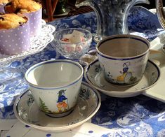 two cups and saucers sitting on a table with other dishes in front of them