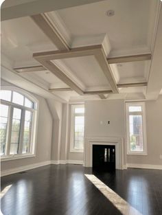 an empty living room with wood floors and white painted walls, two windows on either side of the fireplace