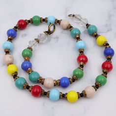 This antique necklace features gorgeous glass rainbow colored beads with brass spacers. This necklace measures 16.5" in length, with the beads measuring 9mm. The clasp and end loop have been replaced. This piece is in good antique condition with some wear. Vintage Multicolor Spacer Beads, Vintage Multicolor Faceted Beads Necklace, Vintage Multicolor Single Strand Necklace, Vintage Glass Beaded Necklaces With Colorful Beads, Vintage Multicolor Necklace With Spacer Beads, Multicolor Vintage Necklace With Spacer Beads, Retro Multicolor Round Beads Necklace, Retro Beaded Necklace With Colorful Round Beads, Vintage Czech Glass Beaded Necklaces With Round Beads