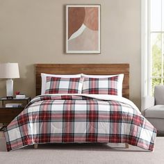 a bed in a room with a plaid comforter and pillows on top of it