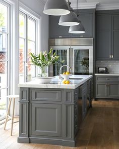 an image of a kitchen with gray cabinets and white counter tops on the left side