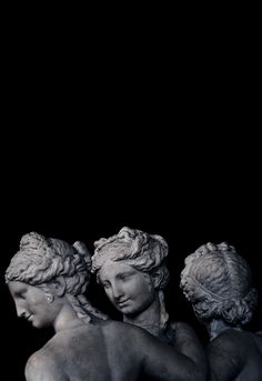 three statues sitting next to each other in front of a black background