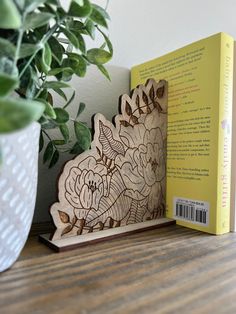 a wooden bookend sitting on top of a table next to a potted plant