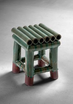 a small green stool with four pipes on it