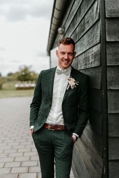 a man in a green suit leaning against a wall