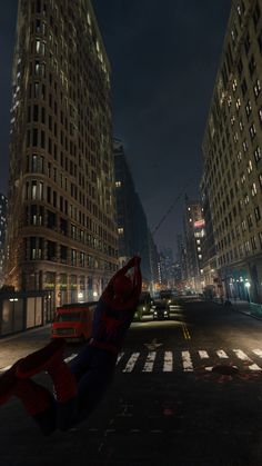 a spider - man in the middle of a city street at night with skyscrapers lit up