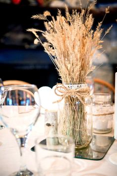 the table is set with wine glasses, candles and flowers in vases on it