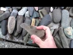 a person holding a piece of metal in front of some rocks and gravel on the ground