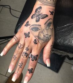 a woman's hand with tattoos on it and butterflies all over the palm area