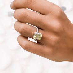 a close up of a person's hand holding a ring with a yellow diamond