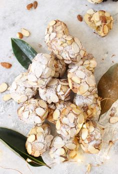 almonds and powdered sugar are piled on top of each other with green leaves