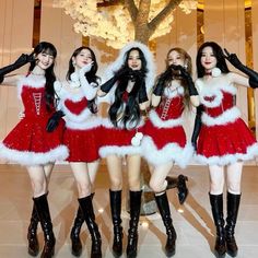 four girls dressed in santa costumes posing for the camera with their hands on their hips