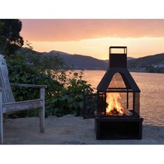 a fire pit sitting on top of a sandy beach next to the ocean at sunset