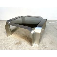 a glass and metal coffee table on concrete floor