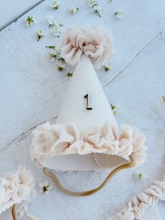 a white hat with flowers on it sitting on top of a table next to other items