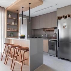 a modern kitchen with stainless steel appliances and wooden stools in front of the counter