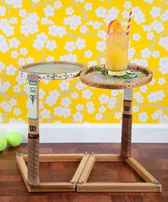 two small trays with drinks on them sitting on a wooden floor in front of a yellow wall