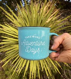 someone holding up a blue coffee mug with the words take more adventure days on it