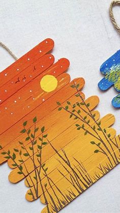 two wooden tags with trees and birds on them, one is painted orange and the other is blue