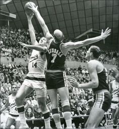 an old photo of two men playing basketball in the middle of a game with spectators watching