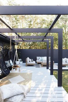 a black and white outdoor patio with hanging chairs, pillows and rugs on the floor