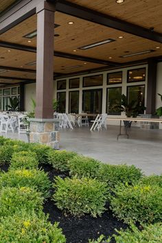 an outdoor patio with tables and chairs in front of a building that has large windows