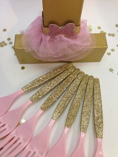 pink and gold hair combs are sitting next to a cardboard box on a table