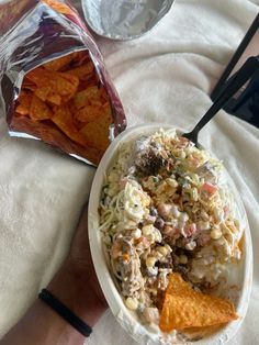 a white bowl filled with chips and coleslaw next to a bag of tortilla chips