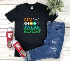 a t - shirt that says aim shot swear repeat on the front, and an image of